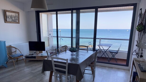 Un comedor con vista al mar, un televisor y un cuadro en la pared.