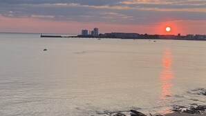 Atardecer costero con aguas tranquilas reflejando el cielo.