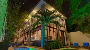 A modern building with large windows, a pool with patterned tiles, and outdoor seating. - Villa/Boutique 4 BDR VIP Concierge/Chef in la Veleta Tulum (La Veleta Tulum)