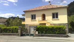 Ein zweistöckiges Haus mit Ziegeldach, einem kleinen Balkon und einem Steinfundament.