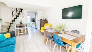 Um espaço de estar moderno com área de jantar, escada e cozinha.