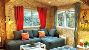 Una sala de estar acogedora con un sofá modular, una mesa de centro y un ventanal con cortinas.