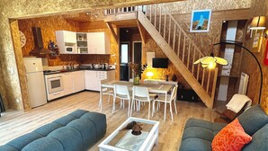 Un área de estar acogedora con un sofá, una mesita de centro y una escalera que sube a una cocina.