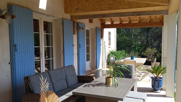 Eine Terrassenanlage im Freien mit Korbmöbeln, einem Tisch und Kübelpflanzen.
