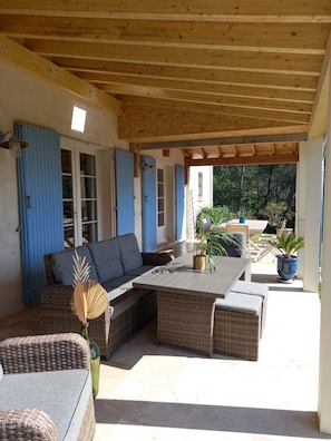 An outdoor patio with wicker furniture, a table, and potted plants.