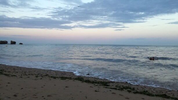 A beach with calm water and a cloudy sky.