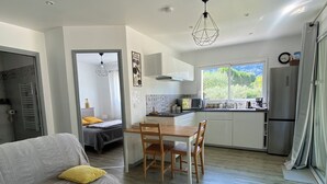 A modern apartment with a dining area, kitchen, and a living room with a sofa and a yellow pillow. - New cottage, with swimming pool facing the Luberon (Robion)