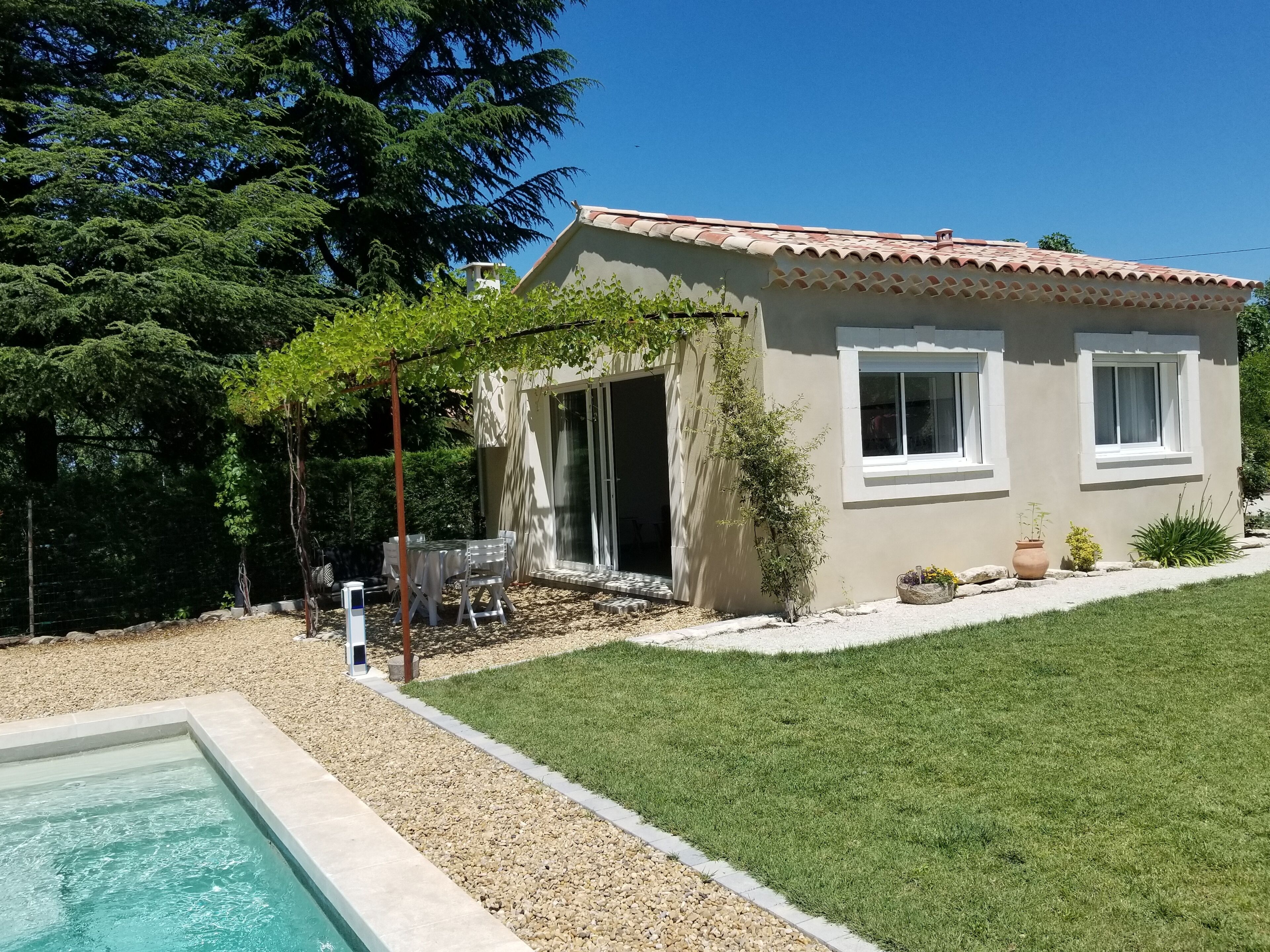 Une maison avec une piscine, une terrasse avec des chaises et un jardin.