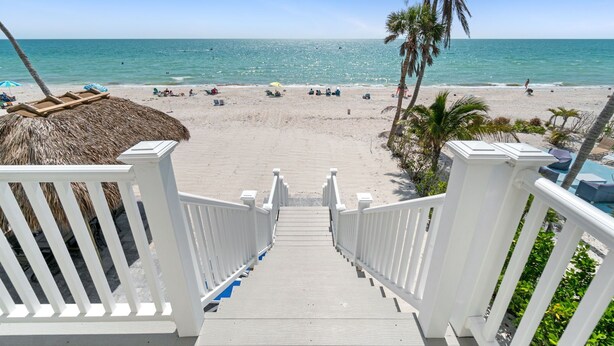 Una escalera de madera que da a una playa con una vista despejada del océano.