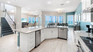 Una cocina moderna con una isla central, muebles blancos y vistas al exterior.