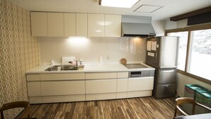 Una cocina compacta con un lavamanos integrado, un refrigerador de acero inoxidable y una ventana que ofrece luz natural.