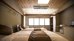 Habitación de hotel con dos camas, techo de madera, un ventanal grande y un escritorio con televisor.