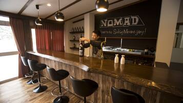 A bar area with a wooden counter, black bar stools, and a sign that reads "NOMAD".