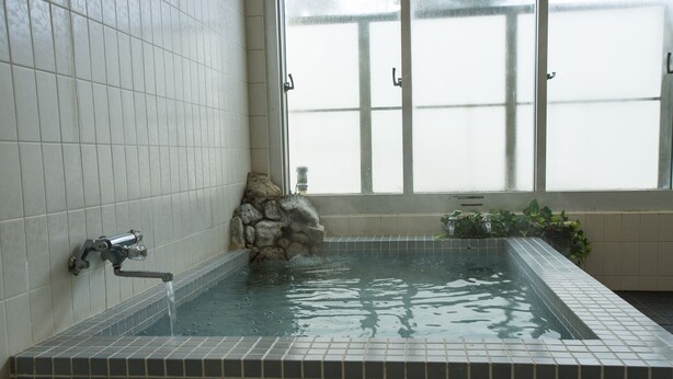 Un espacio de spa con pared de piedra, fuente de agua y ventana con vidrio esmerilado.