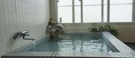 Un espacio de spa con pared de piedra, fuente de agua y ventana con vidrio esmerilado.
