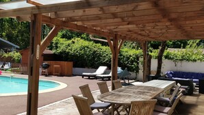 A wooden pergola over a pool area with lounge chairs and a table. - Family villa ideally located on the Basin with heated pool (La Teste-de-Buch)