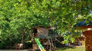 A wooden play structure with a slide and climbing net, surrounded by trees. - Family villa ideally located on the Basin with heated pool (La Teste-de-Buch)