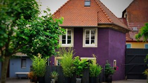 A two-story house with a red-tiled roof and purple walls.