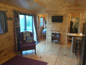 Cozy cabin-style room with a comfortable armchair, flat-screen TV, and dining area.