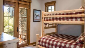 Una cama litera con ropa de cama escocesa, una puerta con marco de piedra y un cartel en la pared.