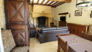 A cozy living room with a fireplace, leather sofa, wooden furniture, and a television. - Charming House in BEYNAC PERIGORD NOIR (Beynac-et-Cazenac)
