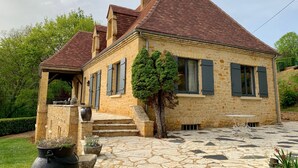 A stone house with a tiled roof, a covered porch, and a paved courtyard. - Charming House in BEYNAC PERIGORD NOIR (Beynac-et-Cazenac)