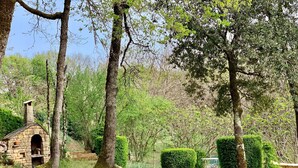 A stone-built structure with a chimney, surrounded by trees and well-maintained hedges. - Charming House in BEYNAC PERIGORD NOIR (Beynac-et-Cazenac)