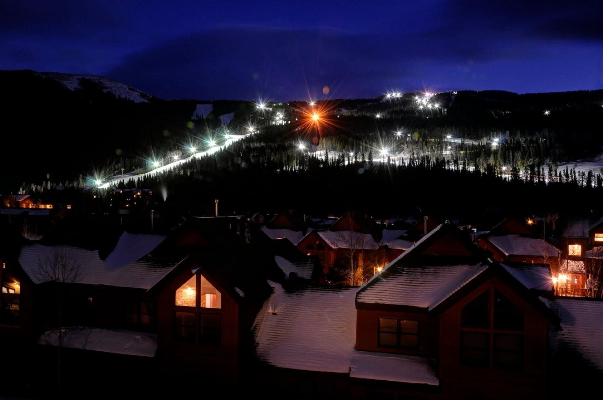 A snow-covered village with houses and a mountain in the background.