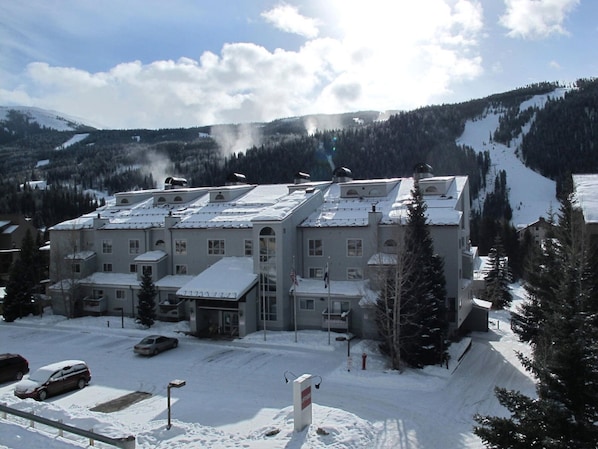 A large building with multiple floors, a parking lot, and a snowy mountain backdrop. - Big 2Br/2 Bath Condo (1443 Sq. Ft.; 2 Living Rooms; Sleeps 10); Walk To Lifts. (Keystone)