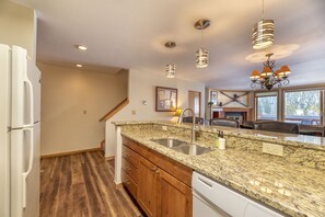A kitchen with granite countertops, a double sink, wooden cabinets, and a built-in dishwasher.