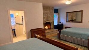 Ein Schlafzimmer mit zwei Betten, einem Kamin, einem Spiegel und einer Tür zu einem Badezimmer.