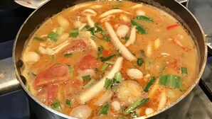 Una olla de sopa con varios ingredientes sobre una estufa.
