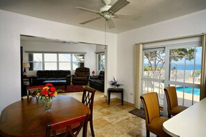 Ein Essbereich mit Tisch, Stühlen und einem Blumenstrauß. Über dem Tisch hängt ein Deckenventilator.