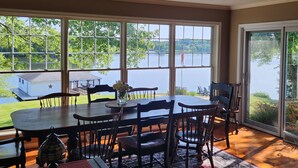 A dining area with a large table and chairs, large windows with a view of a lake and a gazebo, and a ceiling fan. - Main house & guest cottage on over 400 feet of waterfront on the public side (Mineral)