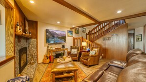 A cozy living room with a fireplace, leather sofa, and a staircase leading to another level.