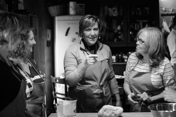 Une cuisine où trois personnes sont en train de discuter, avec un réfrigérateur et divers ustensiles de cuisine.