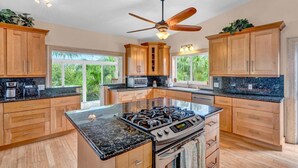 A spacious kitchen with granite countertops, wooden cabinets, a gas stove, and a ceiling fan. - Big Kahuna – an expansive and inviting 5-bedroom, 4-bathroom single-family haven that encapsulates the essence of Florida Keys living (Marathon)
