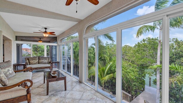 A spacious room with a large sliding glass door leading to a balcony, a ceiling fan, and a seating area with a coffee table. - Big Kahuna – an expansive and inviting 5-bedroom, 4-bathroom single-family haven that encapsulates the essence of Florida Keys living (Marathon)