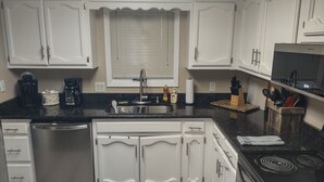 A modern kitchen with white cabinetry, a stainless steel sink, and a black countertop. - CASA LAGO - LAKE FRONT TOWNHOME w/ SPECTACULAR Views w/boat  (Hot Springs)