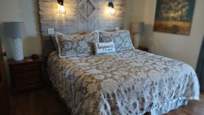 A bedroom with a wooden headboard, two bedside lamps, a floral-patterned bedspread, and a pillow with the word "happiness". - CASA LAGO - LAKE FRONT TOWNHOME w/ SPECTACULAR Views w/boat  (Hot Springs)