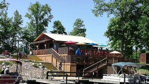 A wooden building with a deck and outdoor seating, a dock with boats, and a clear sky. - CASA LAGO - LAKE FRONT TOWNHOME w/ SPECTACULAR Views w/boat  (Hot Springs)