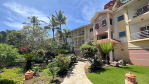 A pathway leading to a building with a garden and palm trees. - Charming Studio in Ocean Dream (Cabarete)