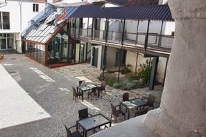 A courtyard with outdoor seating, a glass-enclosed dining area, and a staircase leading to an upper level. - vierzigerhof (Langenlois)