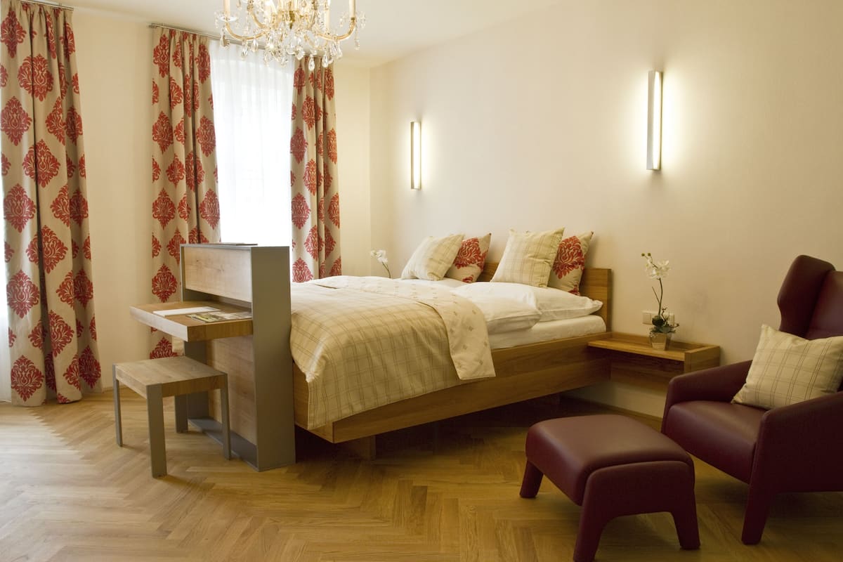 A bedroom with a bed, bedside tables, a desk, a chair, and a bench.