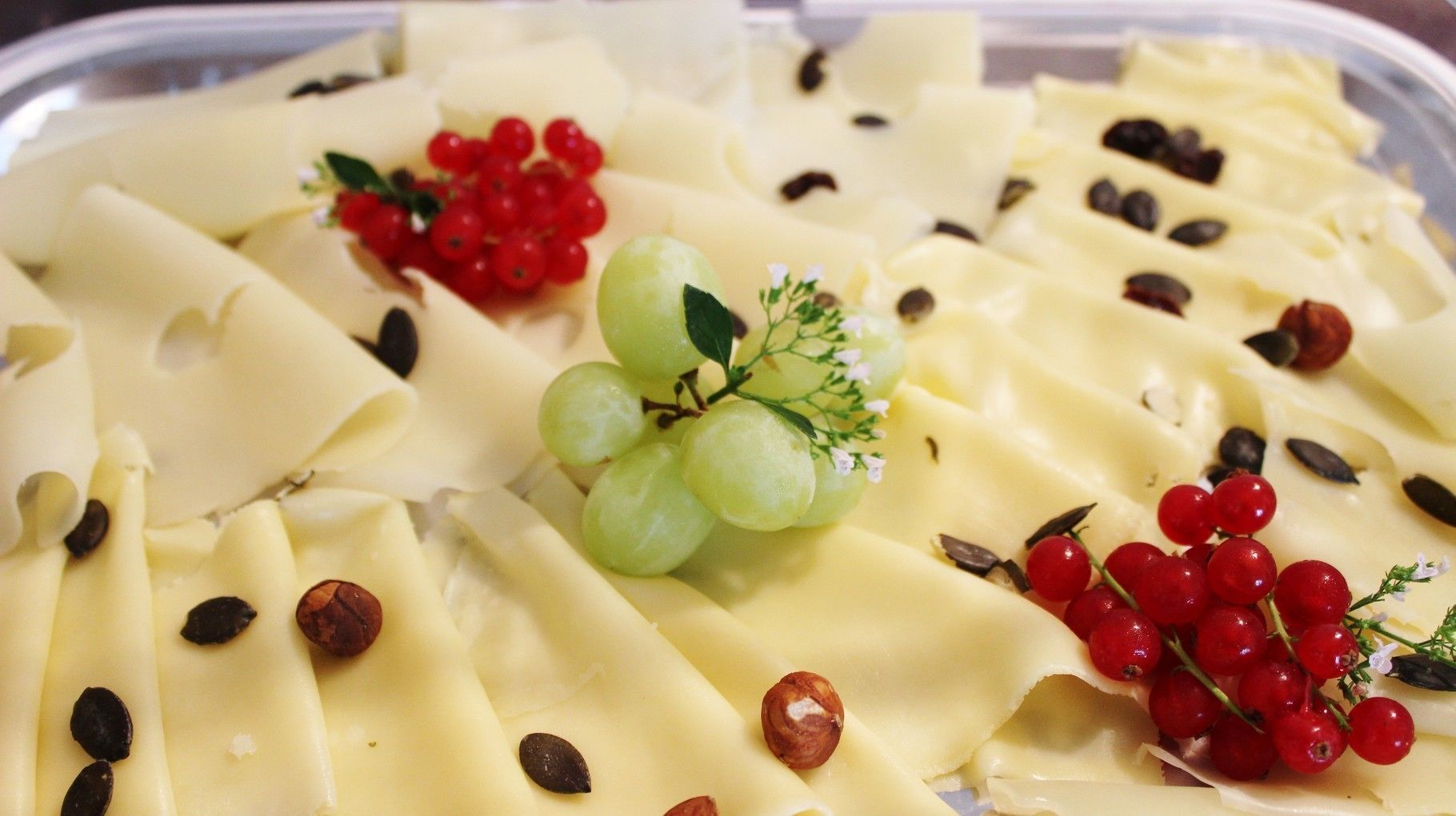 A platter of cheese with grapes and nuts.