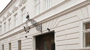 Un edificio con fachada blanca, varias ventanas y un adorno metálico con diseño de gato.
