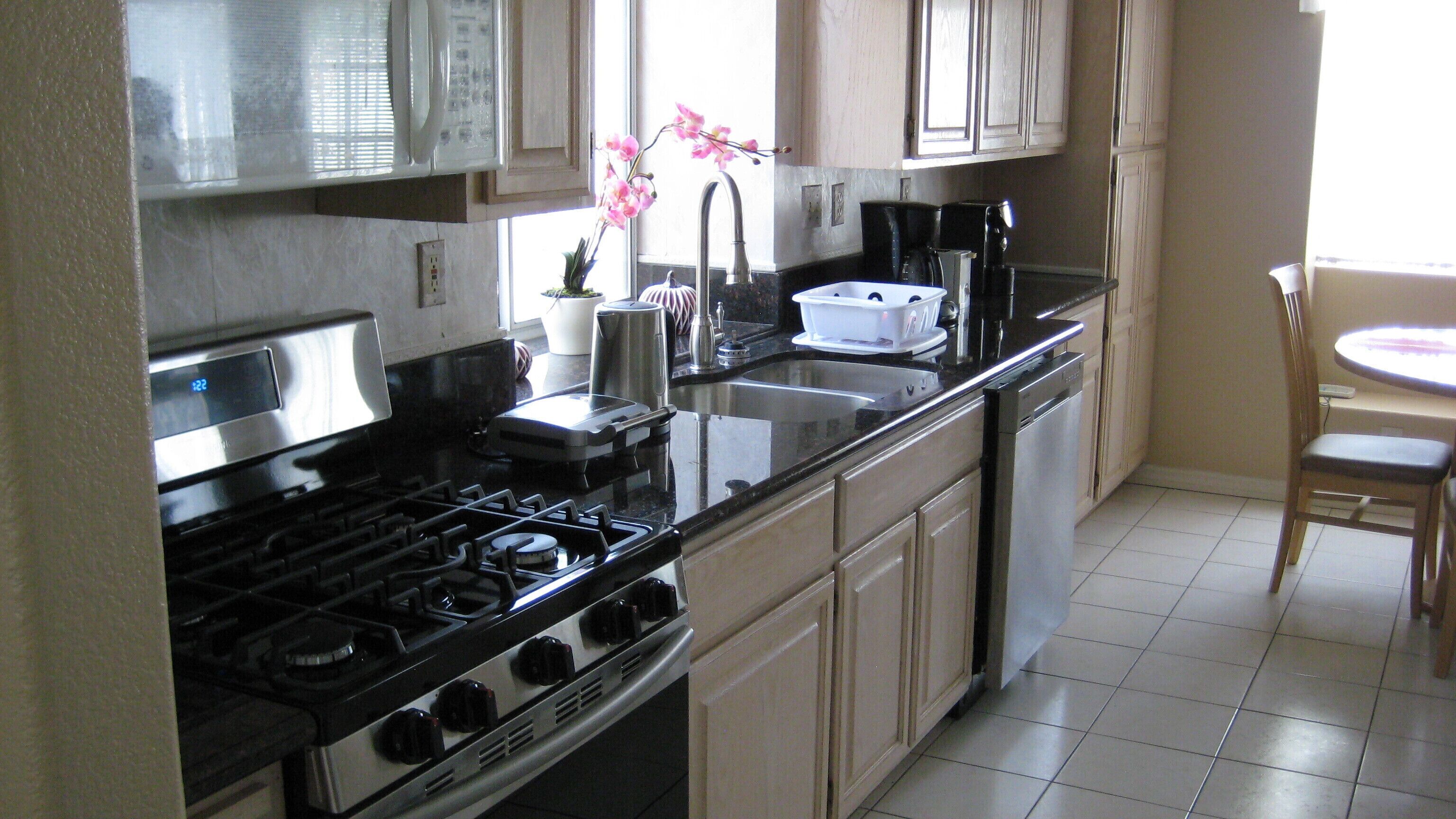 A kitchen with a stove, sink, and cabinets.