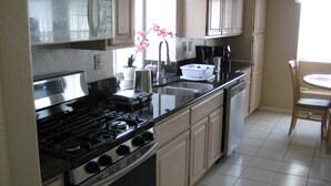 Una cocina con estufa, fregadero y alacenas.