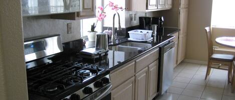 A kitchen with a stove, sink, and cabinets.