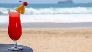 A cocktail on a table with a beach and ocean in the background. - Deluxe Beach Front Villa “Tesoro D” (Ixtapa-Zihuatanejo,)